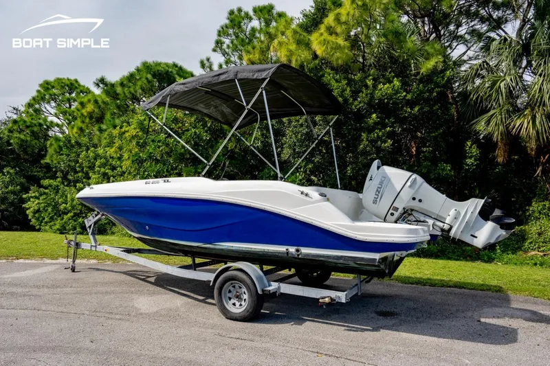 Slide: The Image of 2021 Hurricane SunDeck Sport 205 OB boat on trailer, blue and white, parked outdoors. - 2