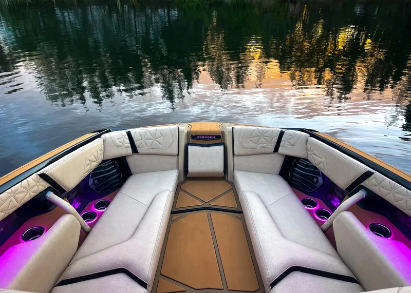 Slide: The Image of 2026 Nautique Paragon G25 boat interior with luxurious seating and ambient lighting on a serene lake. - 12