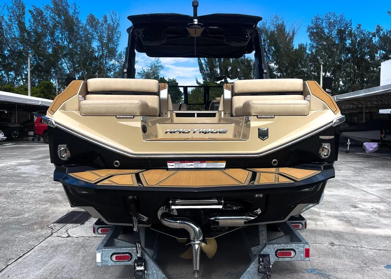 Slide: The Image of 2026 Nautique Paragon G25 boat on trailer, rear view, beige and black design. - 16