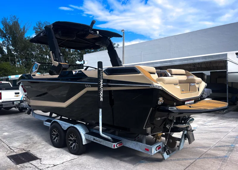 Slide: The Image of 2026 Nautique Paragon G25 boat on trailer, sleek design, parked outdoors under blue sky. - 17