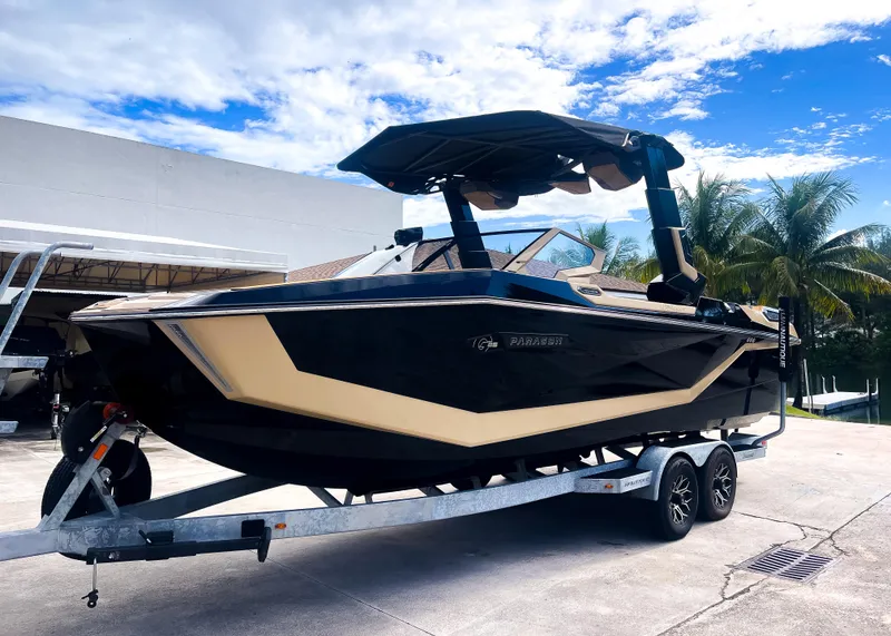 Slide: The Image of 2026 Nautique Paragon G25 boat on trailer, parked outdoors under blue sky. - 18