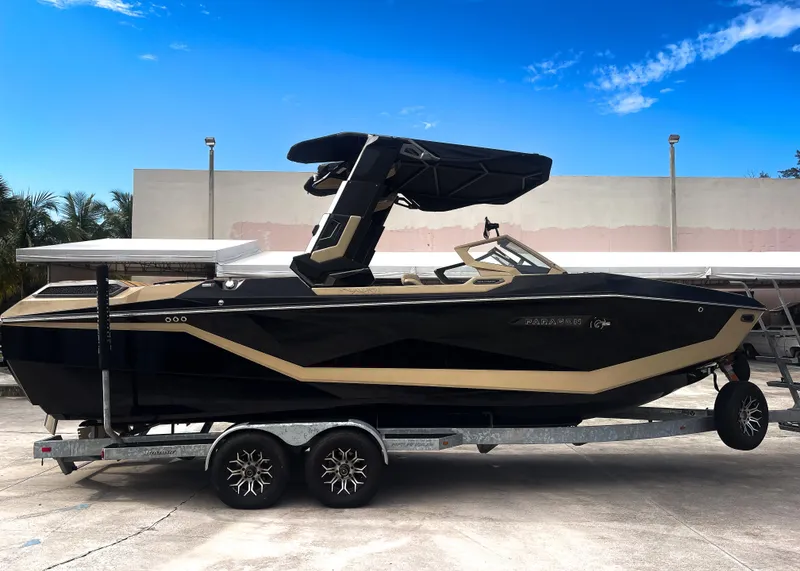 Slide: The Image of 2026 Nautique Paragon G25 boat on trailer, sleek design, black and beige color scheme. - 19
