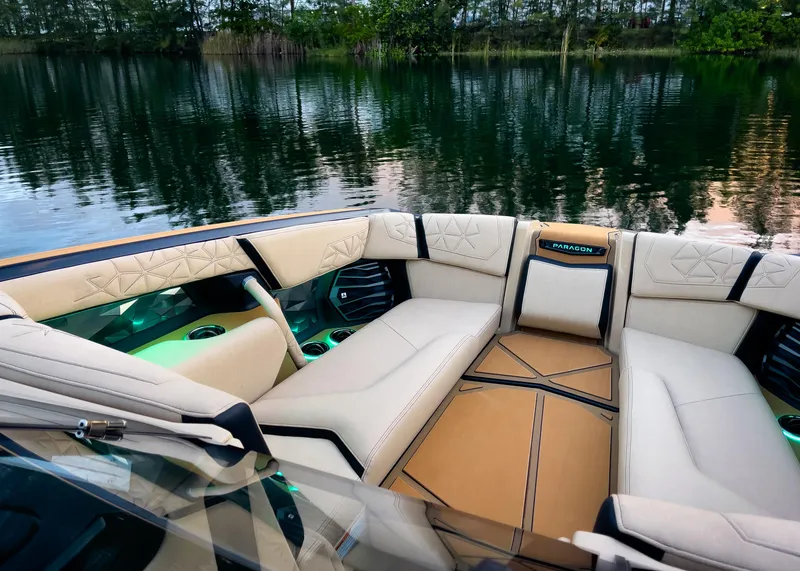 Slide: The Image of Luxurious interior of 2026 Nautique Paragon G25 boat with plush seating by a serene lake. - 4