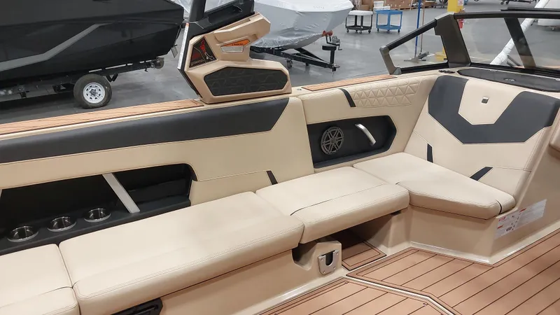 Slide: The Image of 2025 Nautique GS24 boat interior with beige and black seating, cup holders, and modern design. - 12
