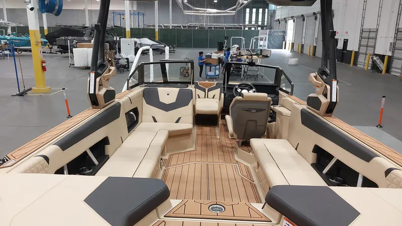 Slide: The Image of 2025 Nautique GS24 boat interior with luxurious seating and modern design in a spacious warehouse. - 14