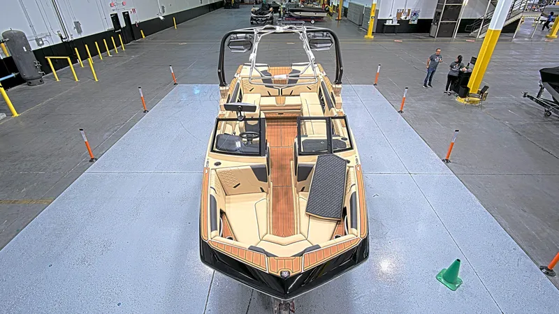 Slide: The Image of 2025 Nautique GS24 boat in a showroom, showcasing sleek design and spacious interior. - 2