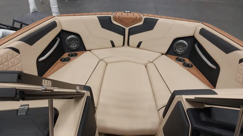 Slide: The Image of 2025 Nautique GS24 boat interior with beige and black seating, cup holders, and speakers. - 8