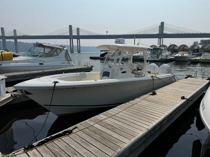 Slide: The Image of 2023 Cobia 301 CC boat docked near a bridge, surrounded by other boats. - 1
