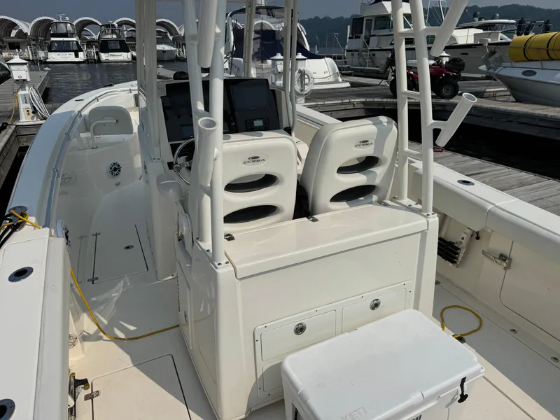 Slide: The Image of 2023 Cobia 301 CC boat interior at marina, featuring helm and seating area. - 10