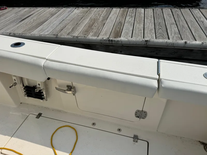 Slide: The Image of 2023 Cobia 301 CC boat interior with white seating and dock in background. - 11