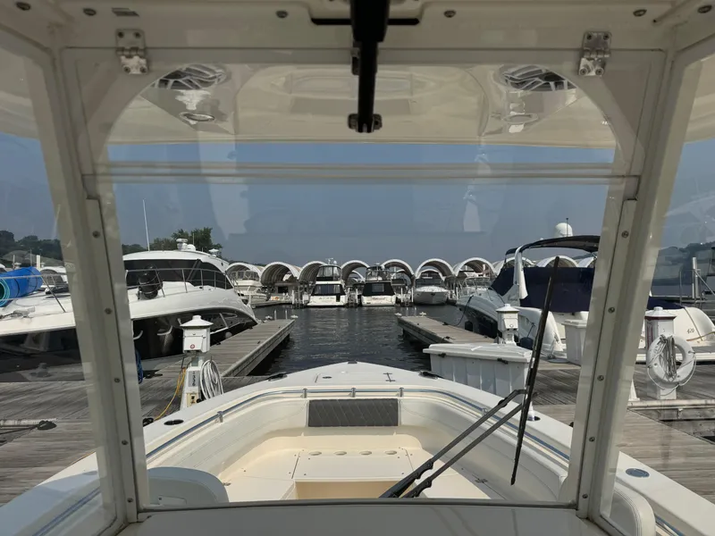 Slide: The Image of 2023 Cobia 301 CC boat docked at marina, surrounded by other boats. - 16