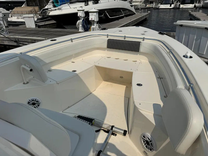 Slide: The Image of 2023 Cobia 301 CC boat interior at marina, featuring spacious seating and modern design. - 17