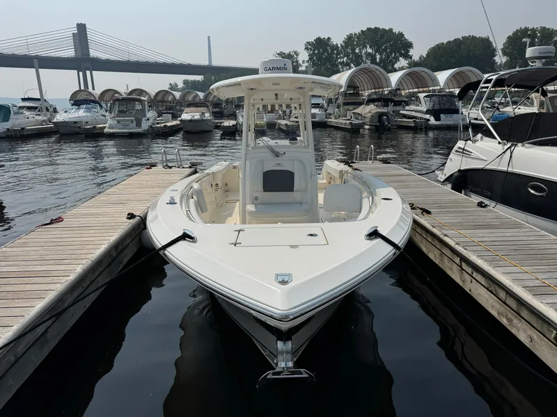 Slide: The Image of 2023 Cobia 301 CC boat docked at marina with bridge in background. - 2