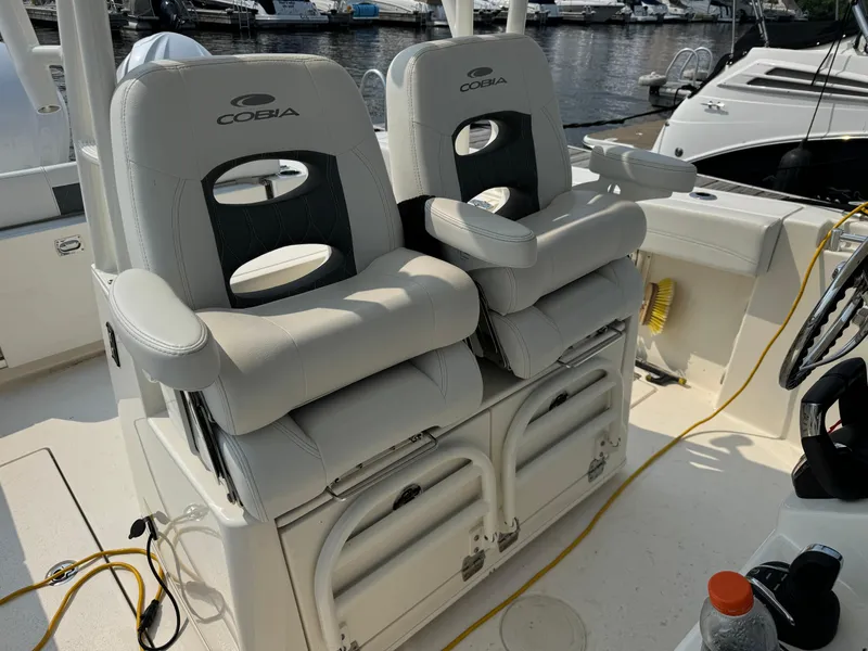 Slide: The Image of 2023 Cobia 301 CC boat seats, white leather, docked at marina. - 21