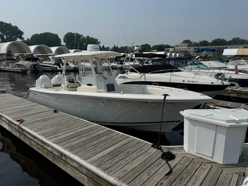 Slide: The Image of 2023 Cobia 301 CC boat docked at a marina with other vessels. - 3