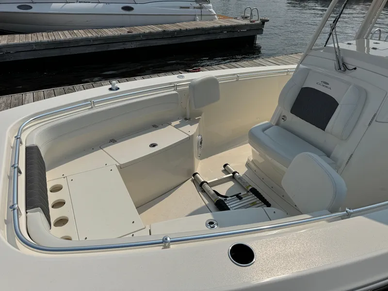 Slide: The Image of 2023 Cobia 301 CC boat interior with seating and storage, docked by the water. - 8