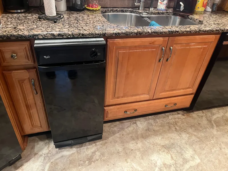 Slide: The Image of Kitchen with granite countertop, wooden cabinets, and a black dishwasher. Majestic 90 X 18, 2003 model. - 20