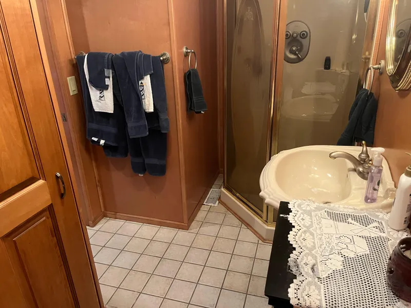 Slide: The Image of Small bathroom with shower, sink, and dark blue towels on a wooden wall. - 30
