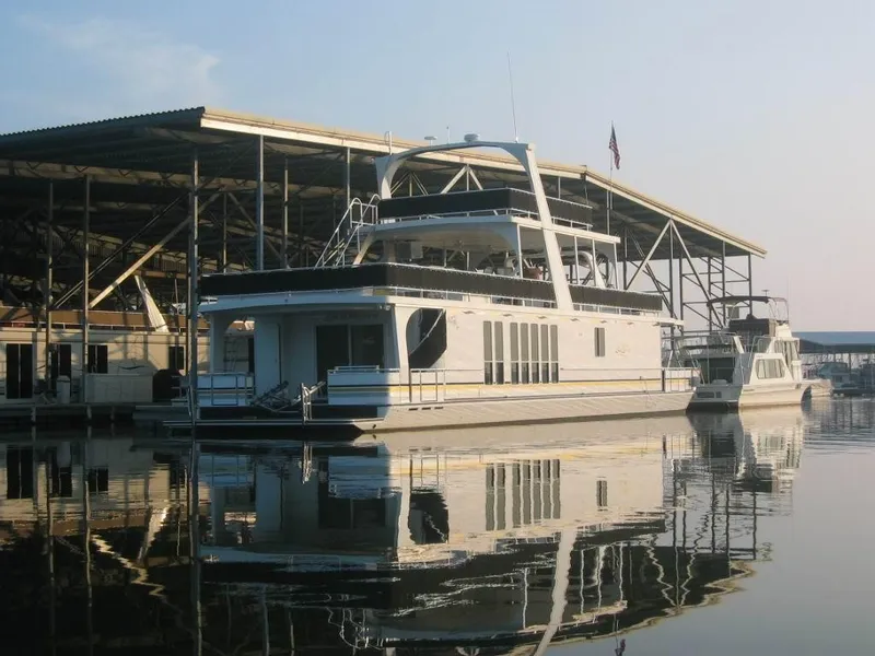 Slide: The Image of 2003 Majestic 90 X 18 houseboat docked at marina, reflecting on calm water. - 4