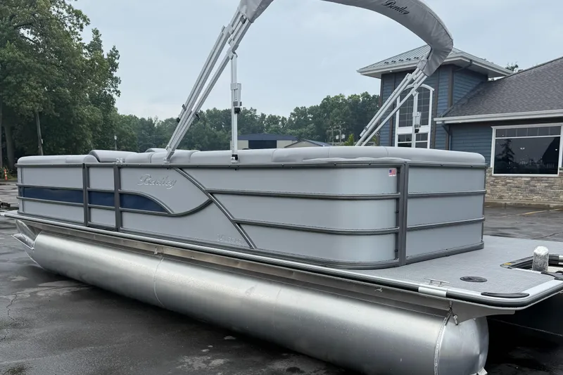 Slide: The Image of 2026 Bentley Pontoons Legacy 240 Cruise XL, sleek design, parked outdoors near a building. - 2