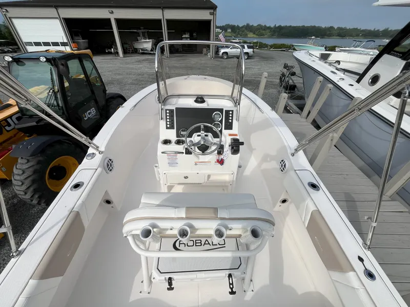 Slide: The Image of 2025 Robalo R180 Center Console boat with outboard motor and rod holders, parked on gravel. - 3