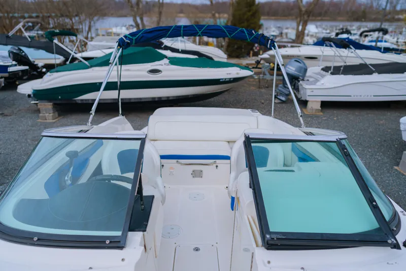 Slide: The Image of 2013 Sea Ray 220 Sundeck boat with blue canopy, parked among other boats. - 5