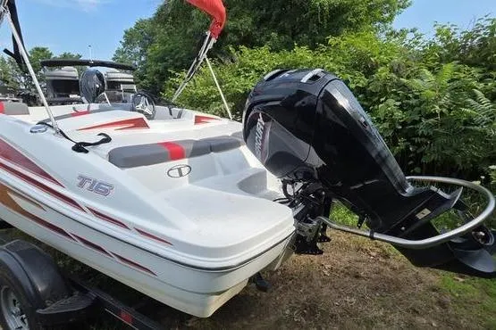 Slide: The Image of 2023 Tahoe T16 boat with outboard motor, parked on trailer, surrounded by greenery. - 6