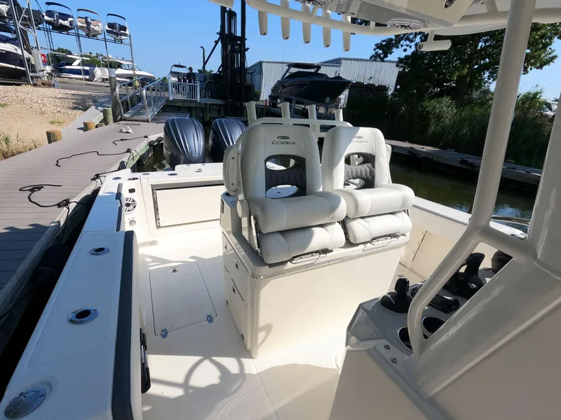 Slide: The Image of 2026 Cobia 285 Center Console boat docked, featuring dual outboard engines and cushioned seating. - 10