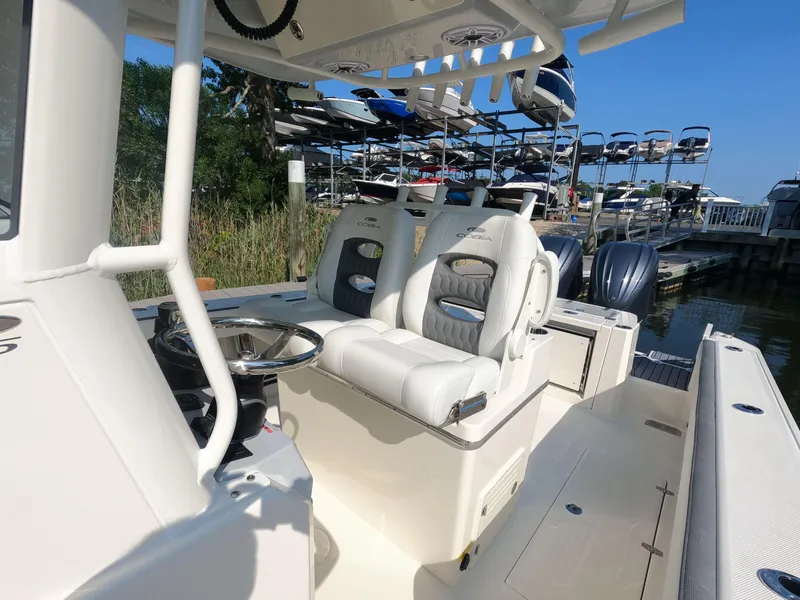 Slide: The Image of 2026 Cobia 285 Center Console boat with dual seats and steering wheel at marina. - 12