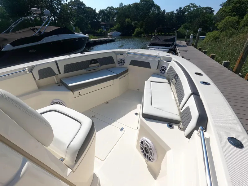 Slide: The Image of 2026 Cobia 285 Center Console boat interior with cushioned seating and speakers, docked by a serene lake. - 17
