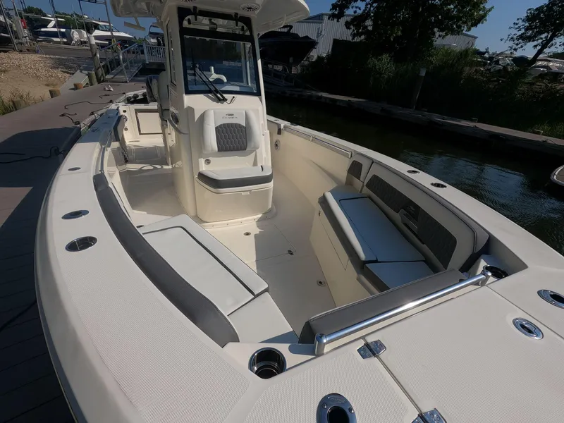 Slide: The Image of 2026 Cobia 285 Center Console boat interior with seating and console, docked by the water. - 18