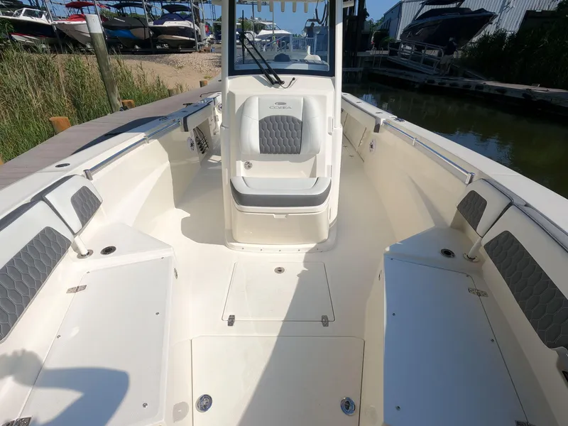 Slide: The Image of 2026 Cobia 285 Center Console boat interior with seating and storage, docked near water. - 19