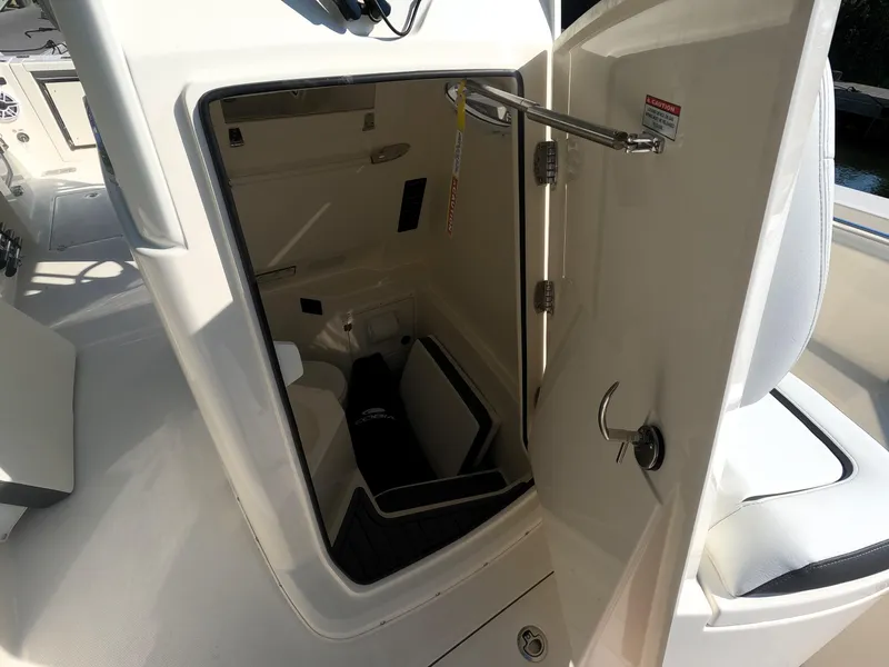 Slide: The Image of 2026 Cobia 285 Center Console interior storage compartment with open door. - 21