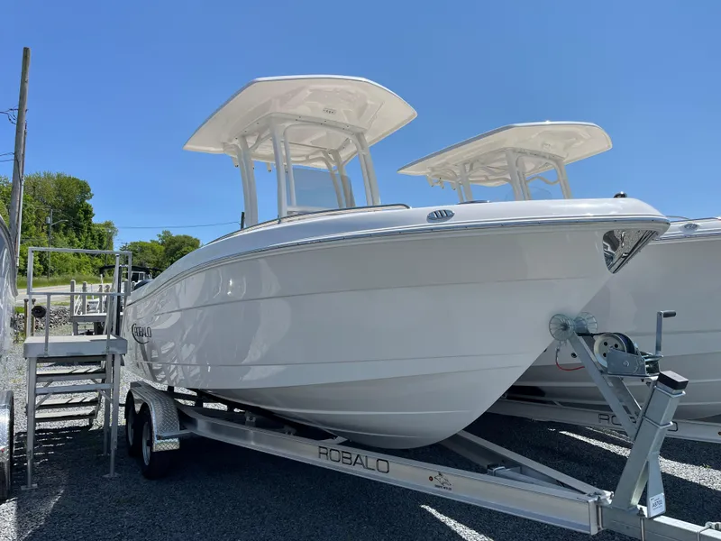 The Image of 2025 Robalo R222 Center Console boat on trailer under clear blue sky. - 1