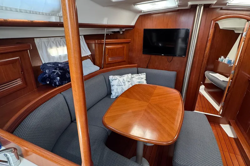 Slide: The Image of Interior of 2003 Beneteau 393 yacht with wooden dining area and cozy seating. - 12