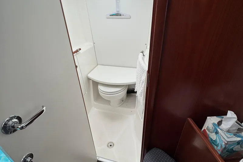 Slide: The Image of Compact bathroom in 2003 Beneteau 393 sailboat with white fixtures and wooden accents. - 14