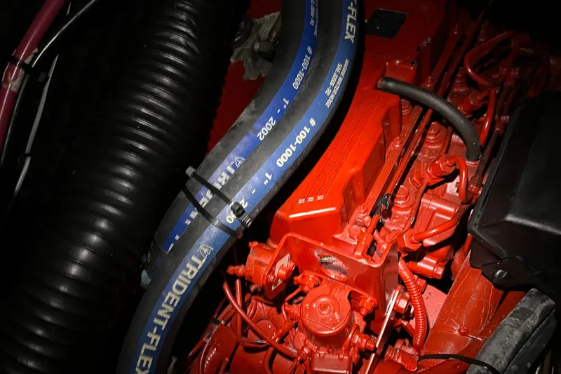 Slide: The Image of Engine compartment of a 2003 Beneteau 393 sailboat, featuring red components and Trident-Flex hose. - 16