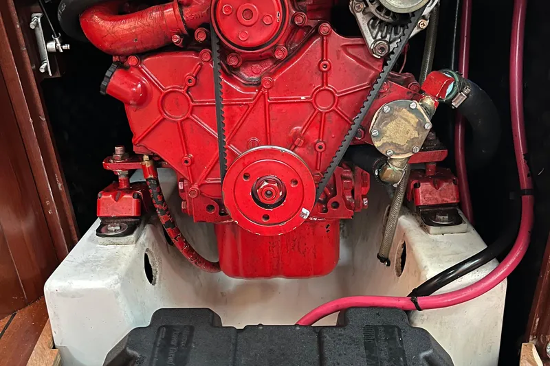 Slide: The Image of Red engine of a 2003 Beneteau 393 sailboat, showcasing mechanical components and hoses. - 17