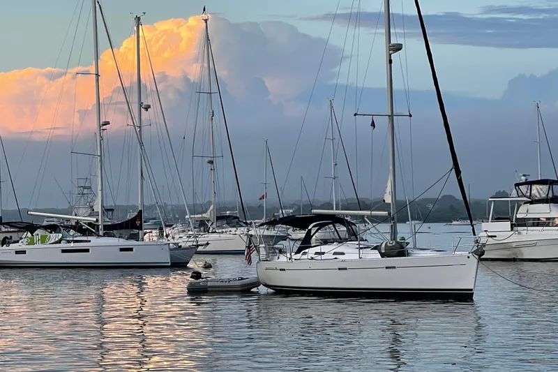 Slide: The Image of Sailboats anchored at sunset, featuring a 2003 Beneteau 393 model. - 2