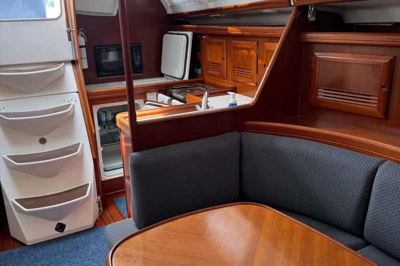 Slide: The Image of Interior of 2003 Beneteau 393 sailboat with wood finish and compact kitchen area. - 8
