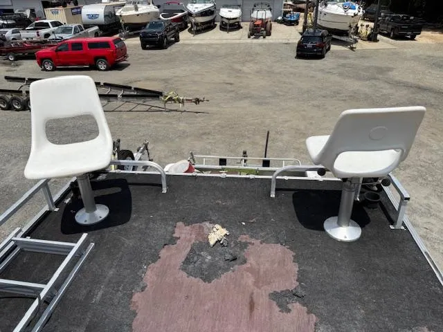 Slide: The Image of Two white seats on a 1998 Crest III 25 boat deck, overlooking a boatyard. - 10