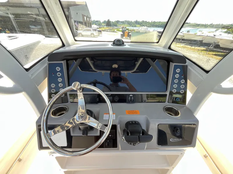 Slide: The Image of 2024 Robalo R250 Center Console boat dashboard with steering wheel and controls. - 8