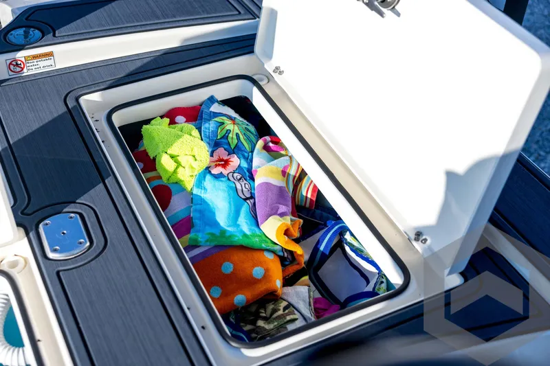Slide: The Image of Open storage compartment on 2026 Pathfinder 2300 HPS boat with colorful towels inside. - 114