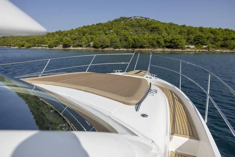 Slide: The Image of Luxurious 2025 Nimbus 405 Flybridge yacht cruising near a lush, green island. - 10