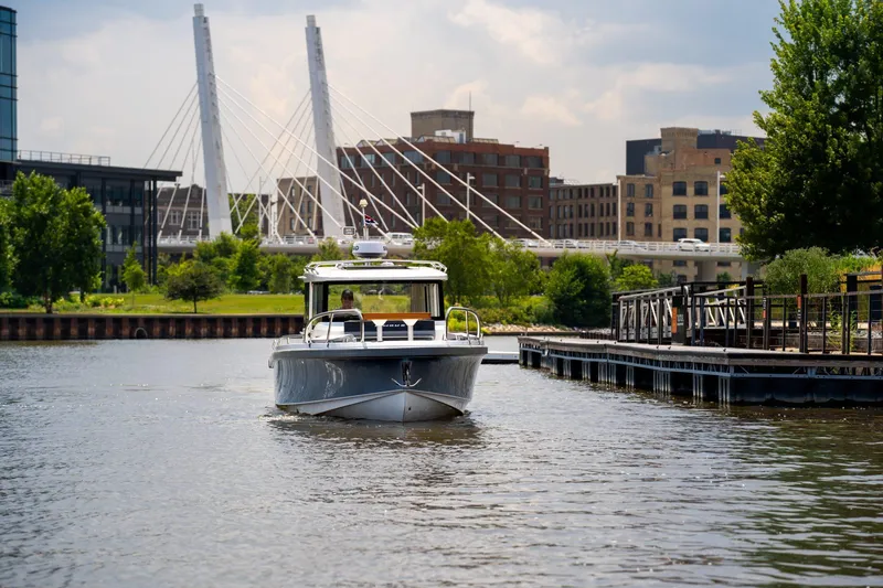 Slide: The Image of Nimbus Commuter 9 boat cruising near urban waterfront with bridge and buildings, 2025 model. - 13