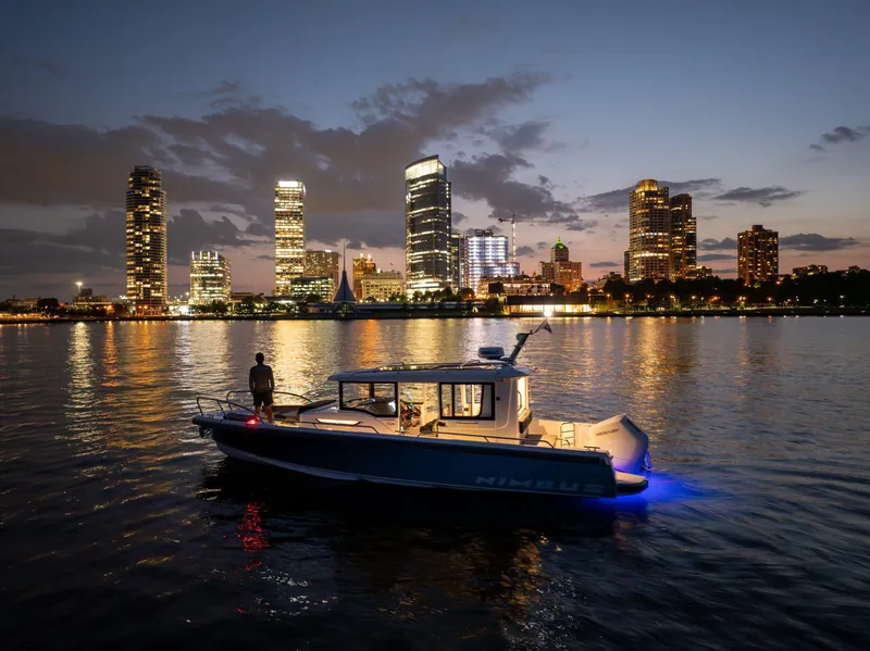 Slide: The Image of Nimbus Commuter 9 boat on water at dusk with city skyline in background, 2025 model. - 4