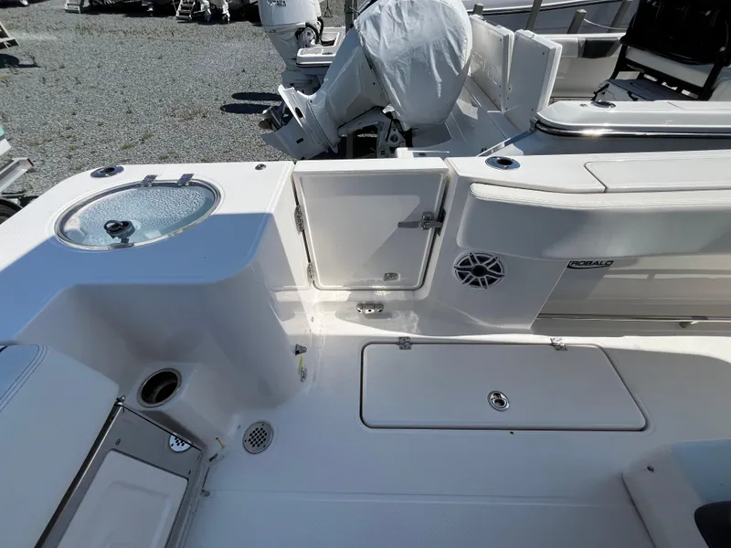 Slide: The Image of 2024 Robalo R270 Center Console boat in a garage, showcasing radar and rod holders. - 4