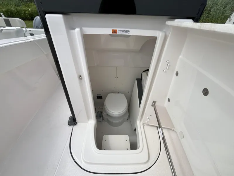 Slide: The Image of 2025 Robalo R270 Center Console boat storage compartment with secure latch and speaker. - 11