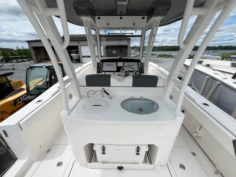 Slide: The Image of 2024 Robalo R302 Center Console boat with T-top and rod holders under cloudy sky. - 3