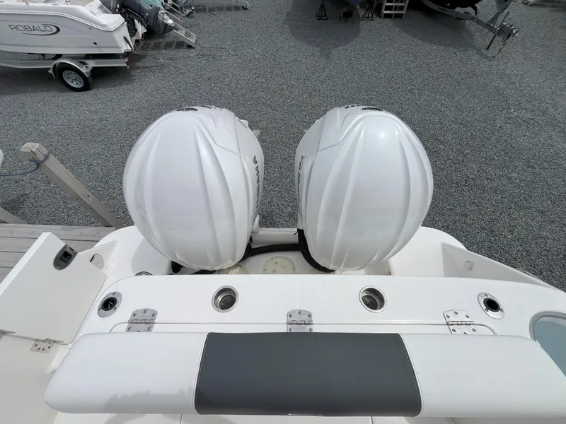 Slide: The Image of 2024 Robalo R302 Center Console boat with open side door, gravel lot background. - 7